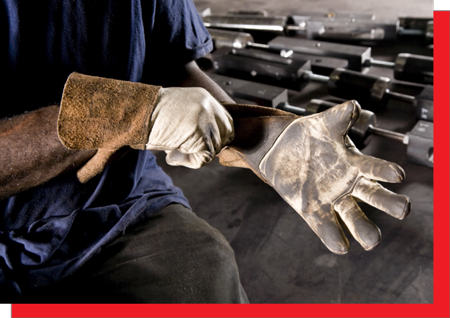 A worker putting on a leather work glove