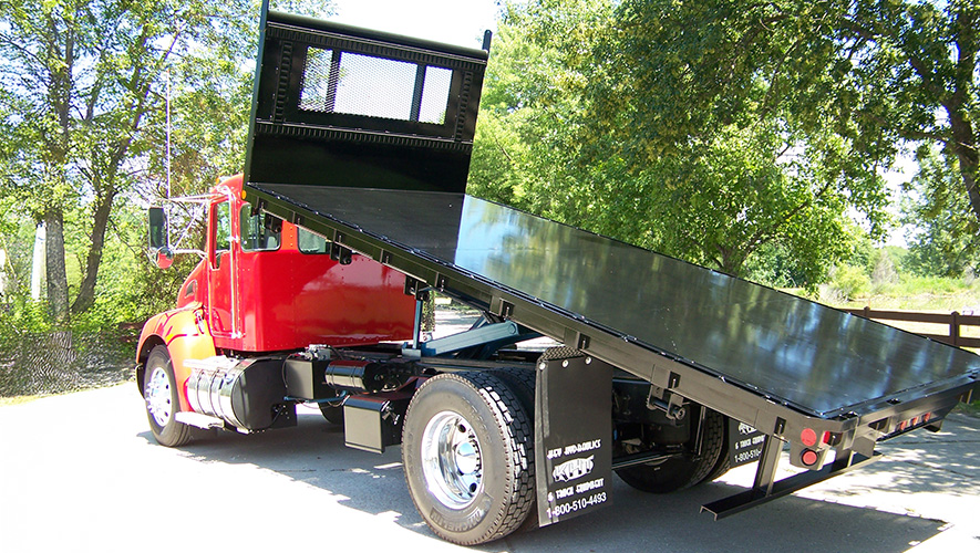 A truck with the truck bed tilted showing the harsh hoist